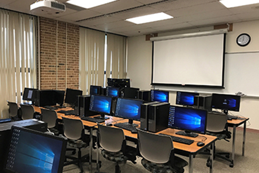 empty computer classroom with tables, chairs and monitors