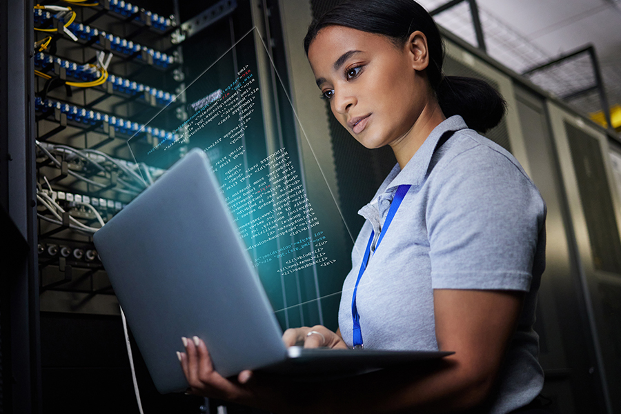 Cybersecurity professional working on a laptop in a server room