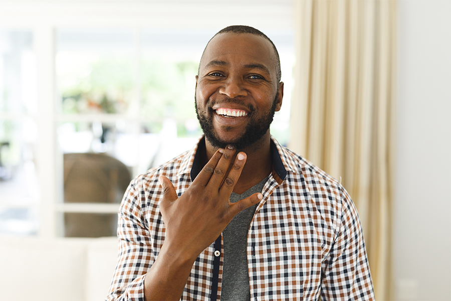 A smiling man in plaid shirt signs thank you.