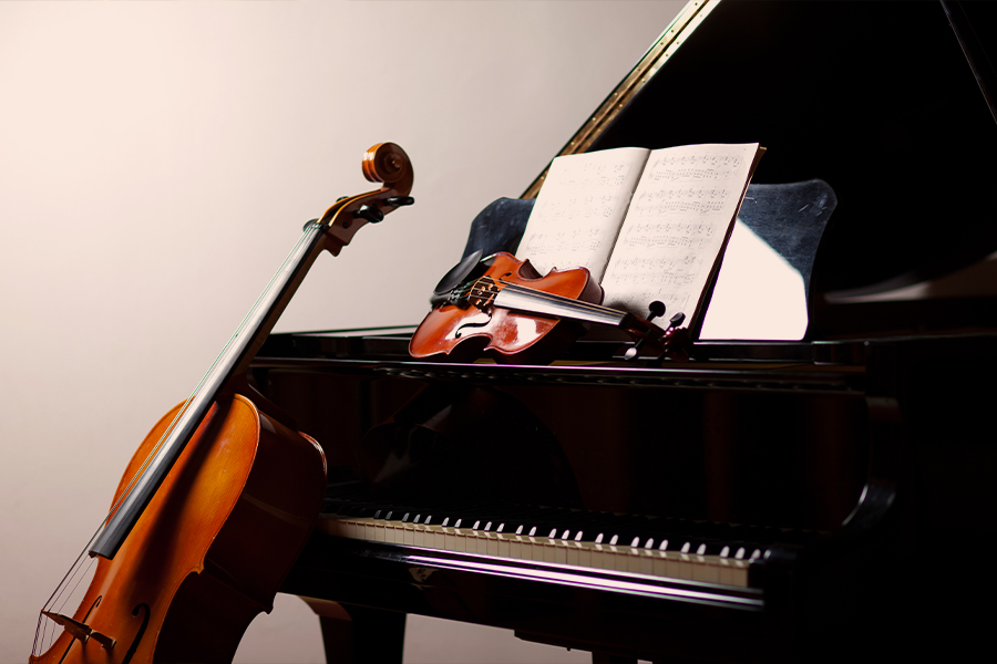 A cello and violin resting on an open grand piano with sheet music on the stand.
