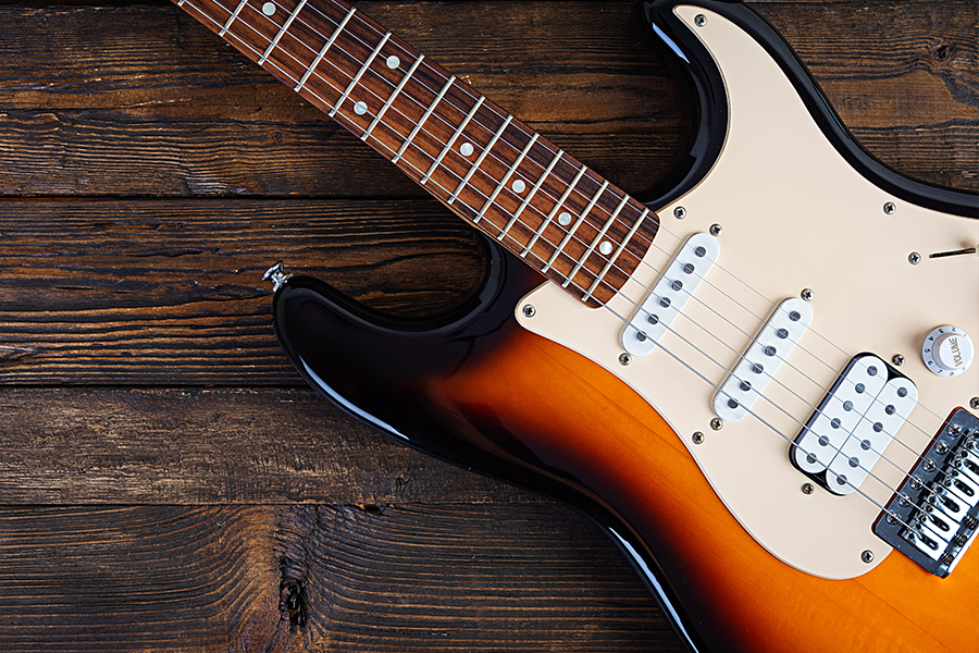 Close-up of an electric guitar body and neck resting on a wooden surface.