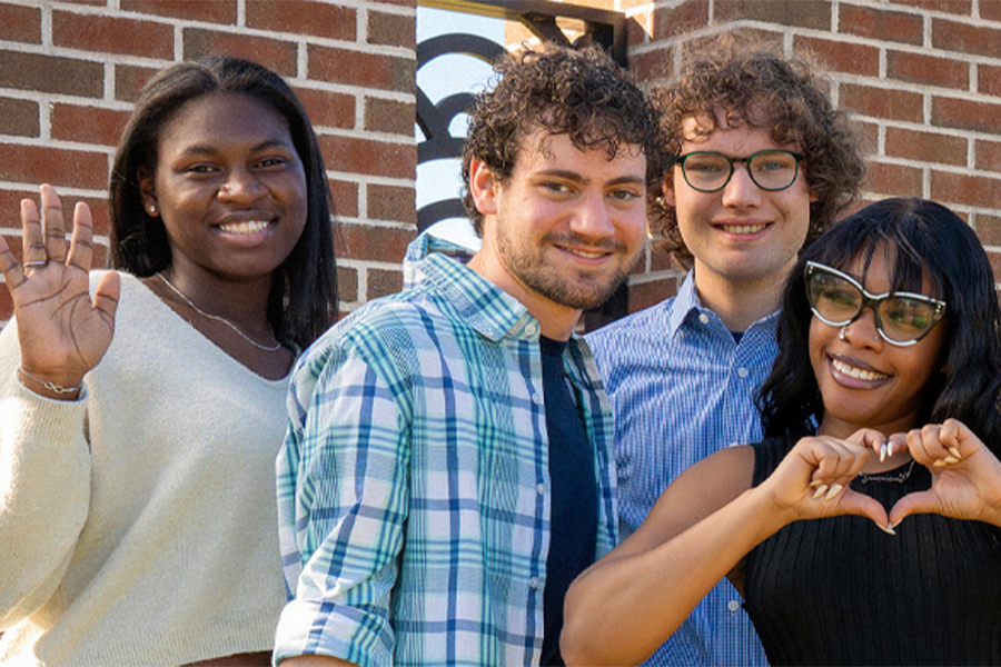 group of smiling students in front of FCC sign making heart with hands