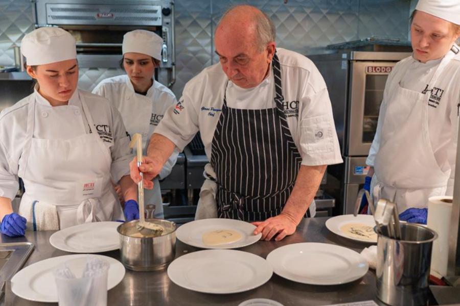  Gemini said A professional head chef demonstrating plating techniques to culinary students in a commercial kitchen.