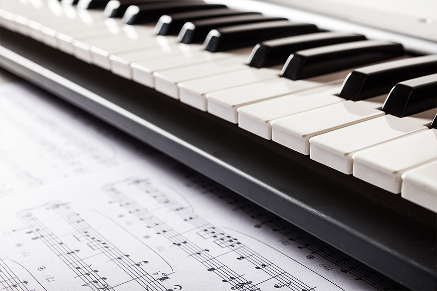 Close-up of piano keys resting on top of printed sheet music.