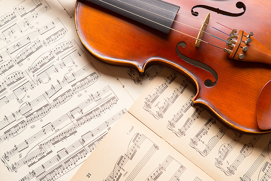 Close-up of a violin resting on open sheet music books.