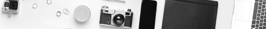 Photography and technology equipment laid out on a white surface, including a vintage film camera, GoPro action camera, smartphone, portable speaker, leather notebook, and laptop. Photography and technology equipment laid out on a white surface, including a vintage film camera, GoPro action camera, smartphone, portable speaker, leather notebook, and laptop.