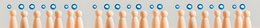 A row of wooden peg figures on a light gray surface, each with a small blue speech bubble icon above them, representing people in conversation and social interaction.
